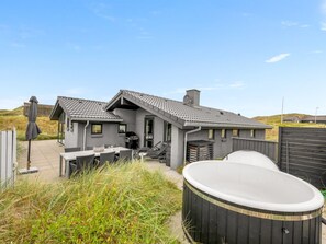 Une maison moderne dotée d’un patio, d’un espace salon extérieur et d’un jacuzzi.