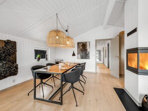 Un espace de salle à manger moderne avec une table et des chaises en bois, un luminaire suspendu et un mur en pierre décoratif.