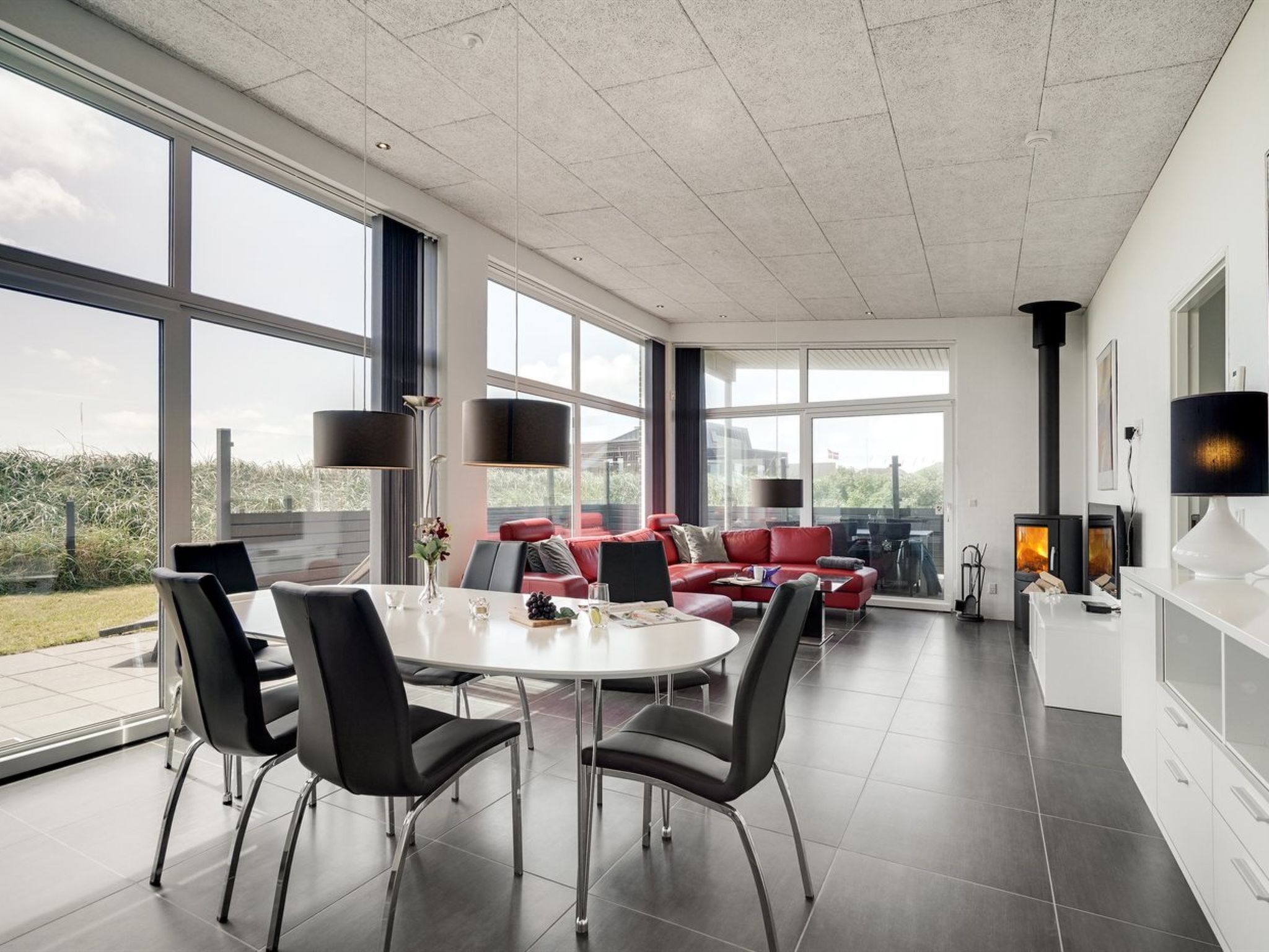 Un salon moderne comprenant un coin repas, de grandes fenêtres, une cheminée et une vue sur l’extérieur.