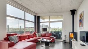 Un salon spacieux avec un canapé d’angle rouge, une table basse en verre et une cheminée.
