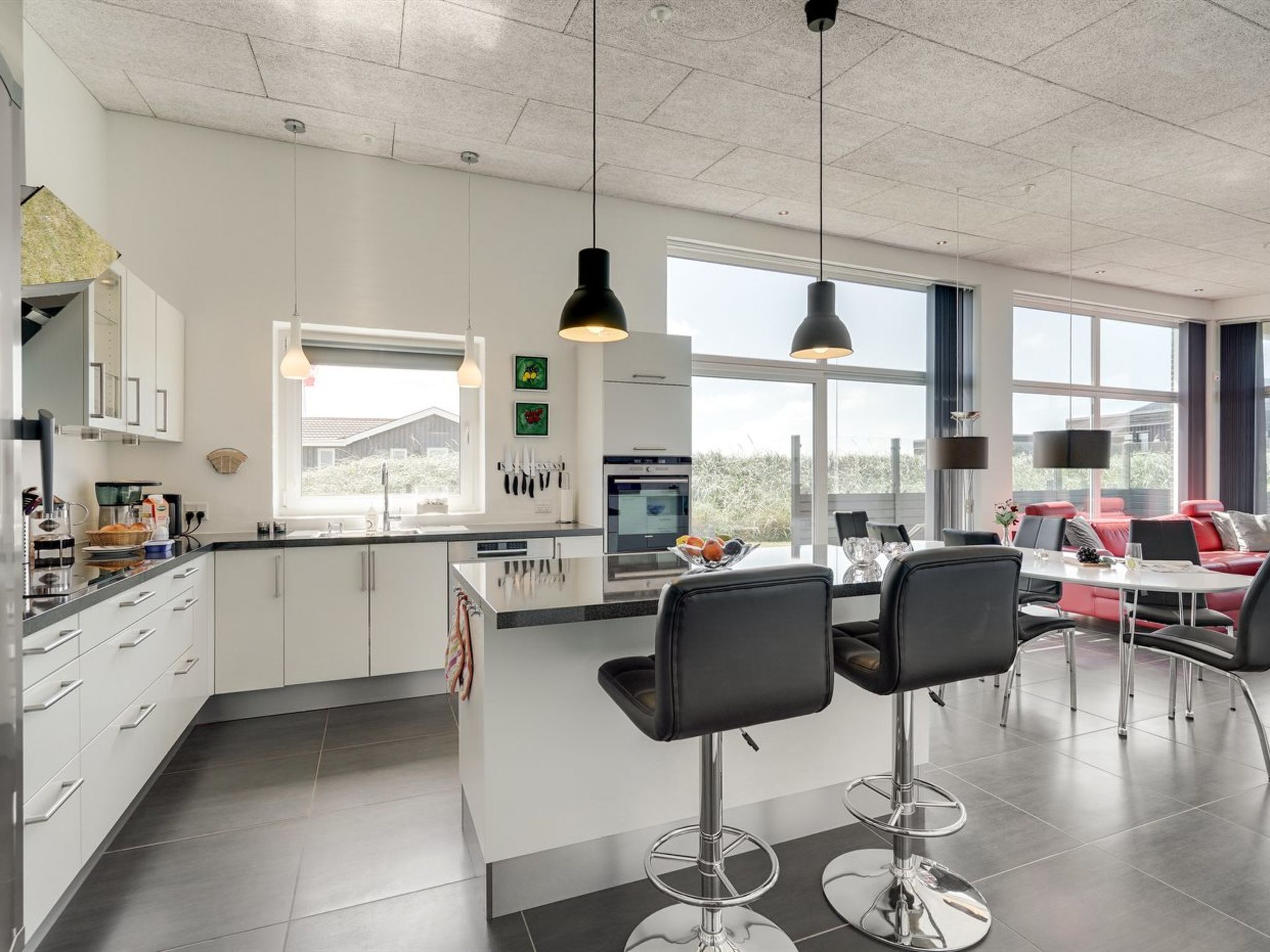 A modern kitchen with a central island, bar stools, and pendant lighting.