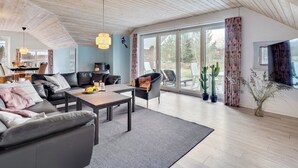 Un salon spacieux au design moderne, comprenant un grand canapé, une table basse et un coin repas avec une table et des chaises.