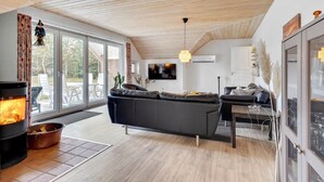 Un salon moderne avec une cheminée, un canapé, une table à manger et un téléviseur.