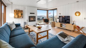 A modern living room with a sofa, a coffee table, a TV, and a fireplace.