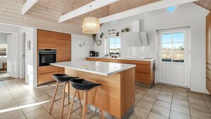 Una cocina moderna con una isla grande, detalles de madera y un tragaluz.