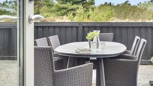 An outdoor patio with a round table and wicker chairs, a small potted plant, and a book. - "Vladan" - 1.6km from the sea by Interhome (Blåvand)