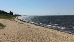 Ein Sandstrand mit blauem Himmel und ruhiger See.