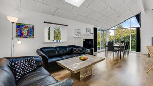 Ein modernes Wohnzimmer mit Sofa, Couchtisch und Essbereich mit Stühlen.