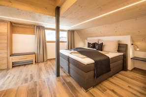 A bedroom with a bed, a bench, a window, and a nightstand. - Apartment 'Superior Xl- 0 Right' with Mountain View, Shared Pool and Wi-Fi (Sand in Taufers)