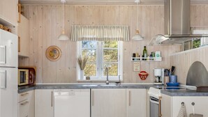 A kitchen with wooden walls, a window with a view, a sink, and a dishwasher.