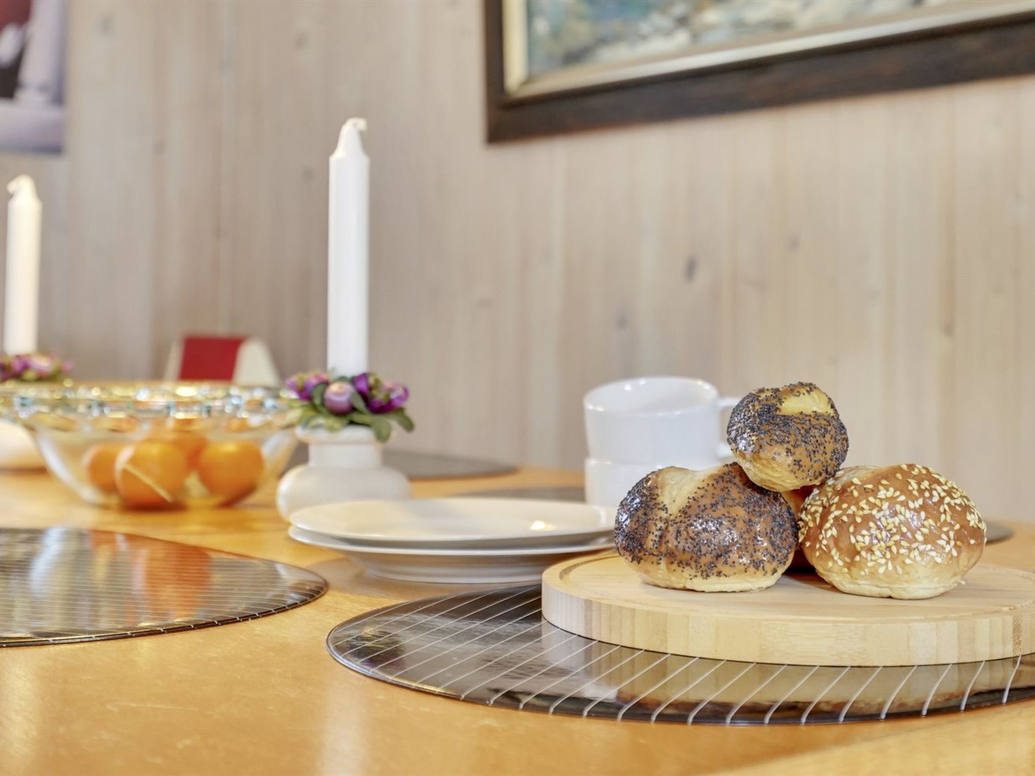 Una mesa con diferentes productos horneados, incluyendo panecillos con semillas, sobre una tabla de madera.