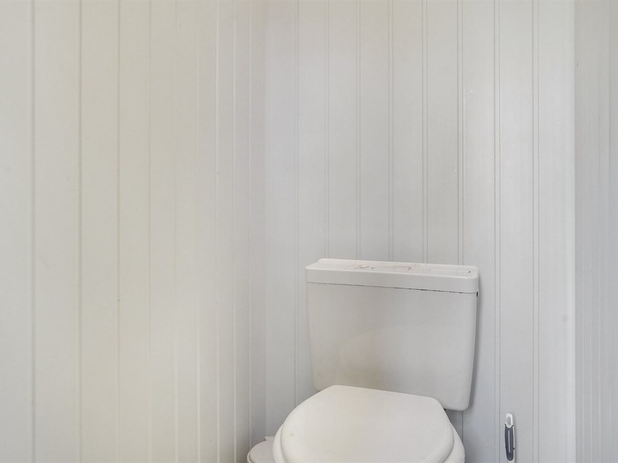 Eine weiße Toilette in einem Badezimmer mit vertikalen Wandverkleidungen.