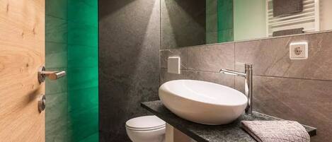 A modern bathroom with a white sink, a towel, and a toilet.