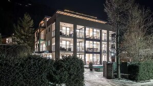 A multi-story hotel with balconies, large windows, and a snow-covered ground.