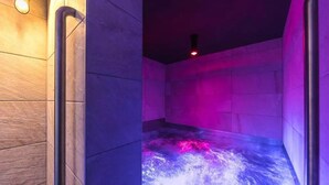 A spa room with a stone wall, a heated floor, and a red light fixture.