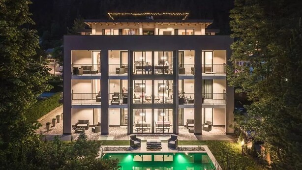 A modern multi-story building with a pool, balconies, and outdoor seating.