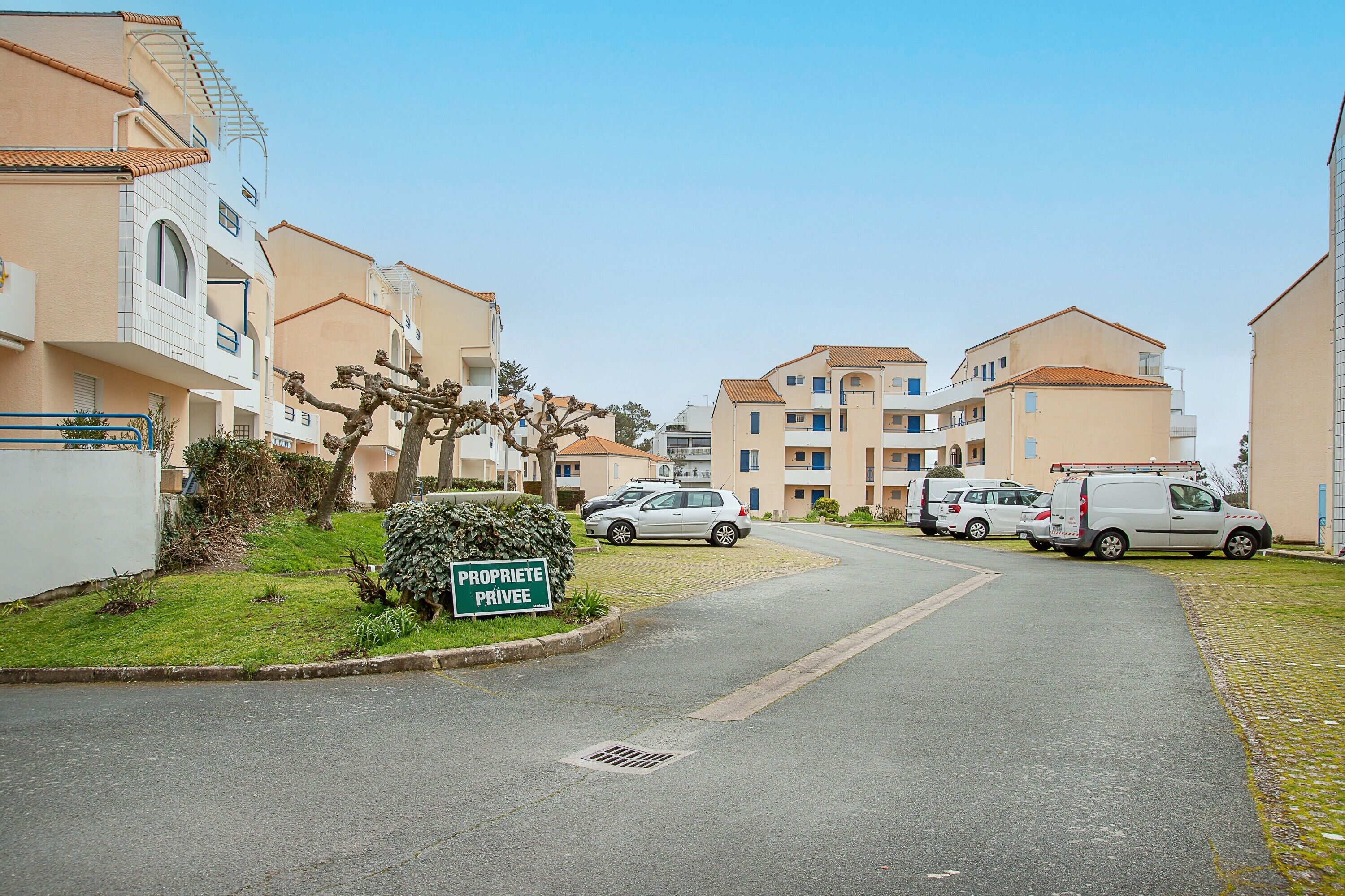 Une rue résidentielle bordée d’immeubles d’appartements, avec une pancarte indiquant « PROPRIÉTÉ PRIVÉE » et des voitures garées.