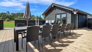 An outdoor deck with a dining table and chairs, a grill, and a hanging planter.