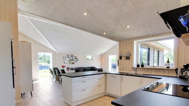 A modern kitchen with a central island, white cabinetry, and a large window providing natural light.