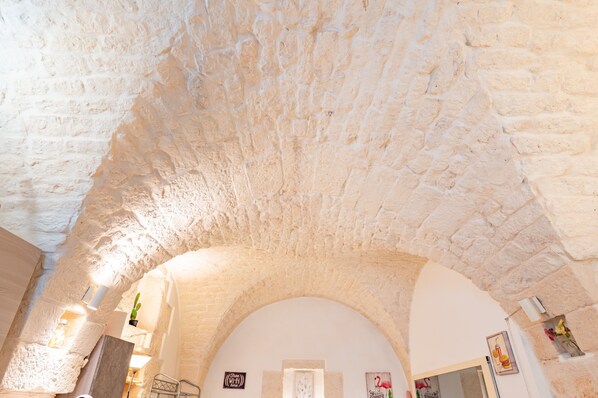 A stone ceiling with an arched doorway, a sign reading 'Welcome,' and a small potted plant.