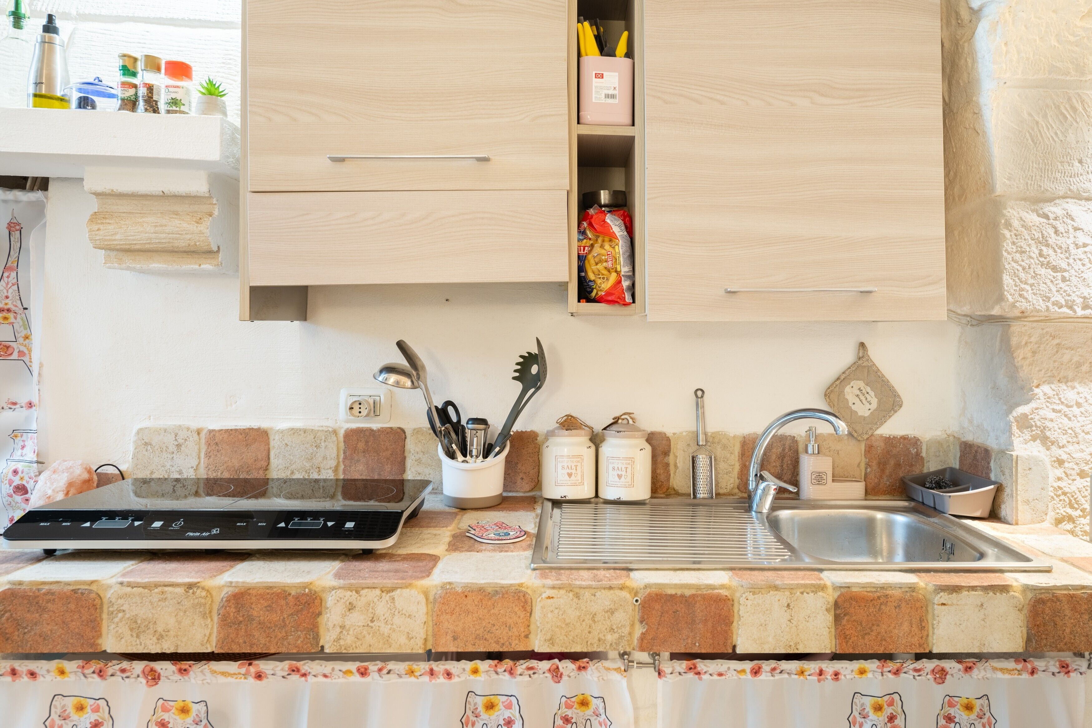 Una cucina con un piano di lavoro, forno a incasso, lavello e pensili.