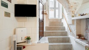 A staircase leading to a landing with a flat-screen TV mounted on the wall, a small air purifier, and a potted plant. - Holiday Home 'Pietrarosa Loft' with Wi-Fi (Ostuni)