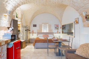 A cozy room with a bed, a dining table, and a kitchen area.