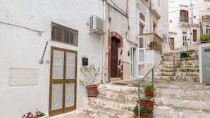 A narrow street with stone steps, a brown door, and potted plants. - Holiday Home 'Pietrarosa Loft' with Wi-Fi (Ostuni)
