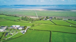 Paisagem rural com campos, estrada e um pequeno conjunto de edifícios.