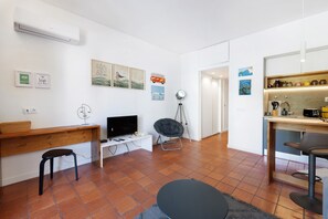 Ett modernt vardagsrum med ett skrivbord i trä, en tv, en stol, en liten pall och en matplats med ett bord och stolar.