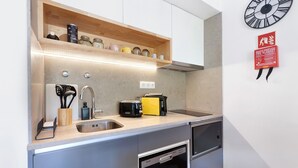 Una cocina con un lavamanos de acero inoxidable, un tostador, una cafetera y una manta ignífuga en la pared.