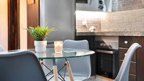 A modern kitchen with a glass table, chairs, a potted plant, and a lit candle. - Vacation Home "Ático Miranda" with Jacuzzi, Views of El Teide & Wi-Fi (Icod de los Vinos)