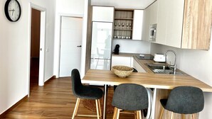 Una cocina moderna con encimera de madera, un fregadero y una zona de comedor con sillas.
