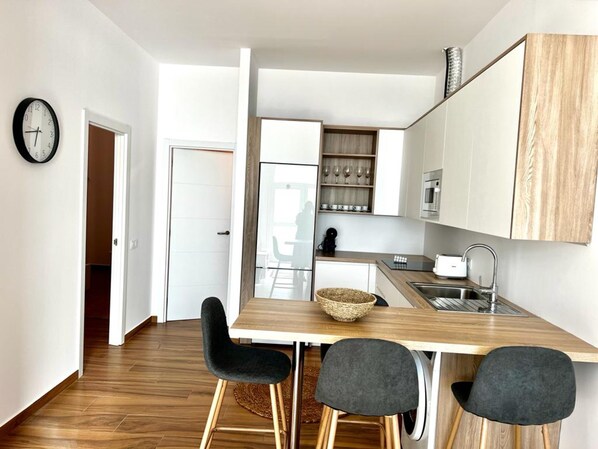 A modern kitchen with a wooden countertop, a sink, and a dining area with chairs.