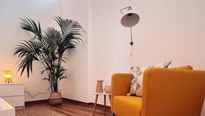 Un salón moderno con un sillón amarillo, una planta en maceta, una mesita auxiliar y una lámpara de pie.