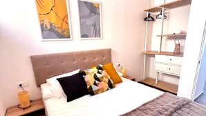 A bedroom with a bed, nightstands, a wardrobe, and abstract wall art. - Vacation Home "Amber L5" with Sea View & Wi-Fi (Armeñime)