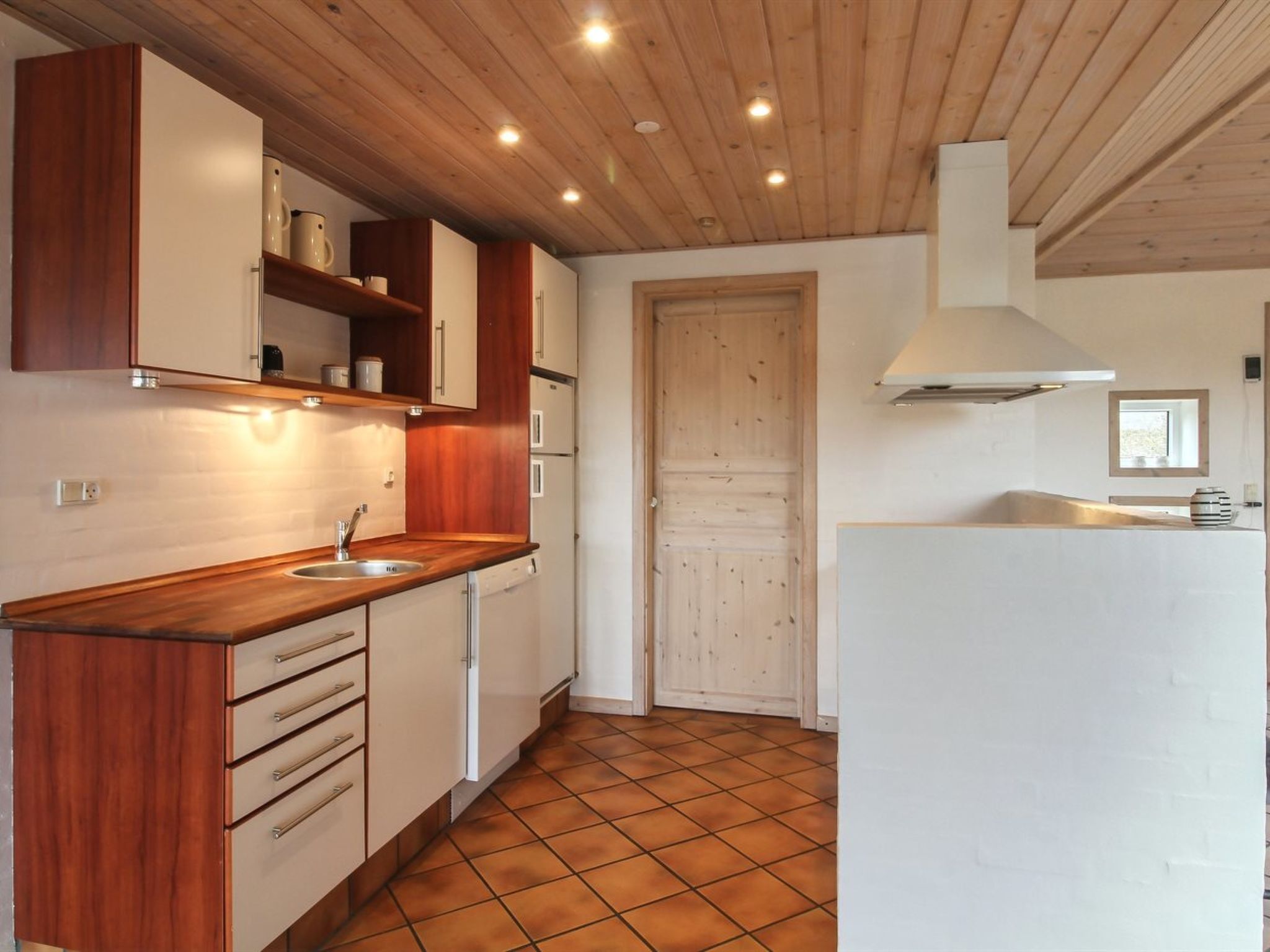 A compact kitchen with wooden cabinets, a sink, and a tiled floor.