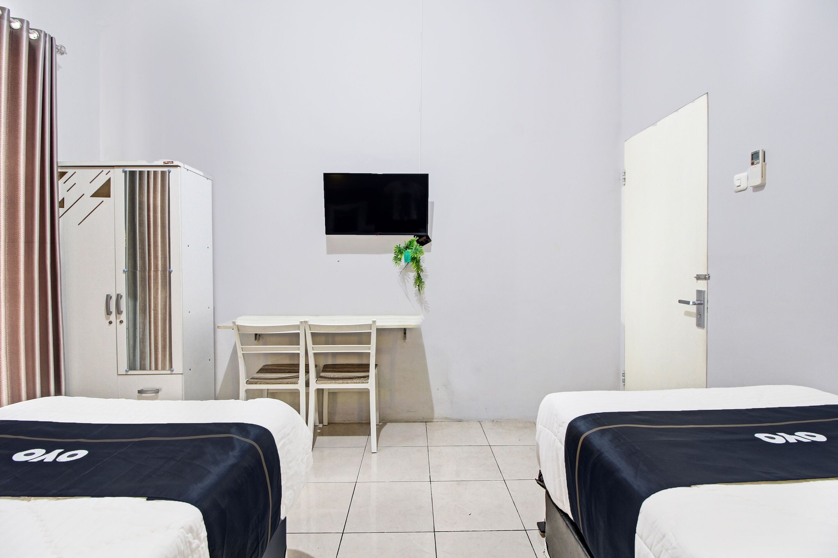 A hotel room with two beds, a desk, a TV, and a wardrobe.