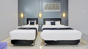 Una habitación de hotel con dos camas, una pared de acento gris y una obra enmarcada sobre las camas.