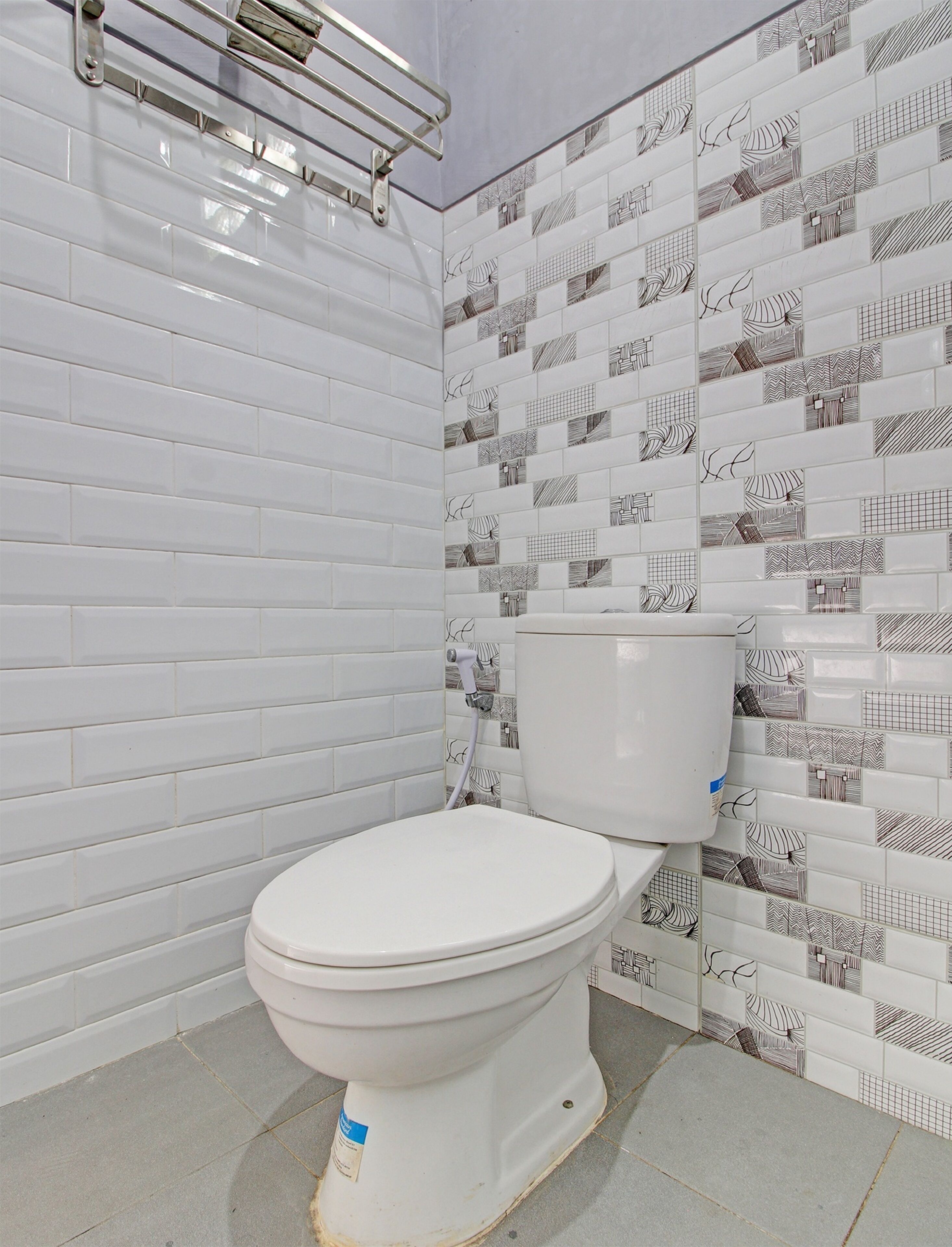 A bathroom with a white toilet, tiled walls, and a metal towel rack.