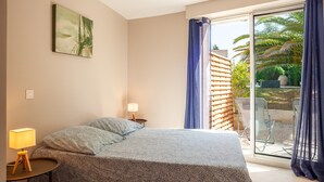 Quarto com cama, mesa de cabeceira, luminária, janela com cortinas e vista para o exterior.