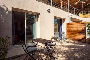 An outdoor patio with a table and chairs, a wooden fence, and a sliding glass door leading to an interior space. - Apartment 'Cocon Avec Piscine Et Jardin' with Shared Pool, Private Terrace and Wi-Fi (Marseille)
