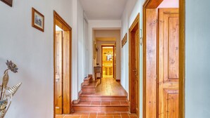 A hallway with wooden doors, a tiled floor, and a staircase leading to another room. - Villa Marta Apartment: Nature, Tranquility, and Authentic Umbrian Charm (Spoleto)
