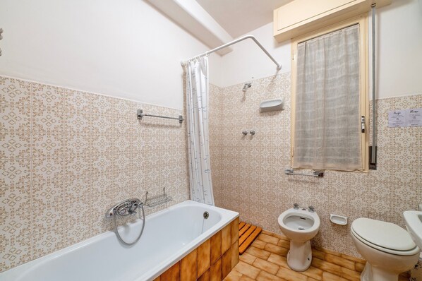 A bathroom with a bathtub, a shower, a toilet, and a bidet.