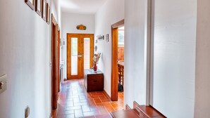 A hallway with wooden doors, a tiled floor, and a small table with a vase. - Villa Marta Apartment: Nature, Tranquility, and Authentic Umbrian Charm (Spoleto)