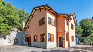 A two-story building with a stone foundation, multiple windows with wooden shutters, and a clear sky. - Villa Marta Apartment: Nature, Tranquility, and Authentic Umbrian Charm (Spoleto)