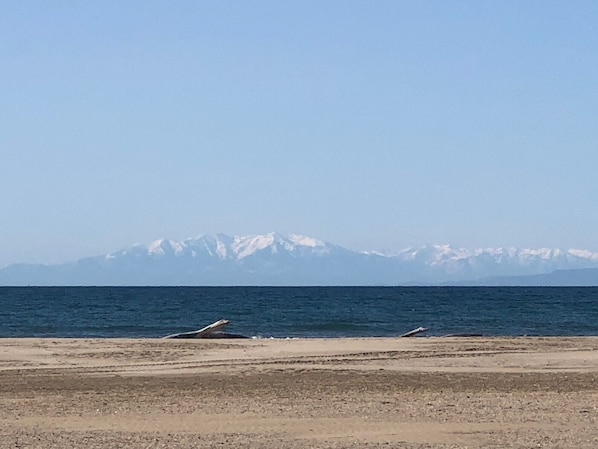 A beach with a clear view of snow-capped mountains in the distance.