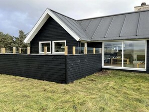 A modern house with a black exterior, a sloped roof, and large windows.