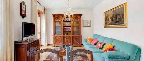 Una sala de estar con un sofá azul turquesa, un mueble de madera y un televisor.