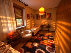 A bedroom with a bed, a chair, a desk, and a radiator.